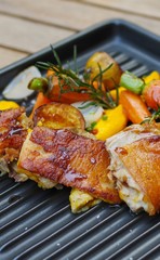 Roasted chicken with small baby carrots, potatoes, rosemary, garlic and mango sauce on black iron tray top view