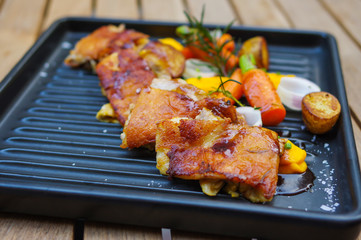 Chicken barbecue with baby carrots, garlic, potatoes, rosemary and mango sauce on black oven tray top view