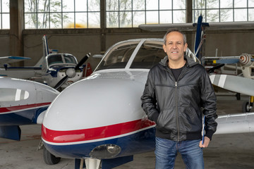 Smiling Pilot in front of Small Airplane in a Hangar