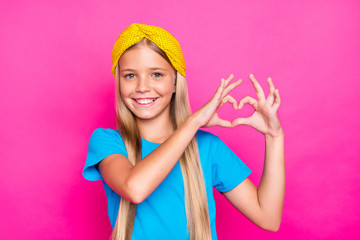 Fototapeta na wymiar Portrait of lovely positive cheerful kid make heart from her finger sign of passionate affectionate love to her father mother wear blue clothes isolated over pink color background
