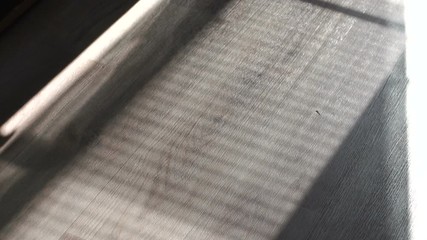 Shade from the blinds on the wooden floor with laminate or parquet. Thin lines of light on the floor. Shadow from the blinds. Abstract of light and shadow on a floor through window blind shutter.