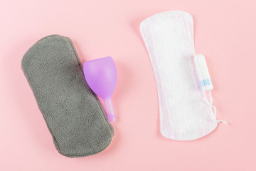 Reusable eco-friendly female pad, menstrual cup, tampon and usual women's pad. Pink background, place for text, minimalism, top view, flat lay. Zero waste concept