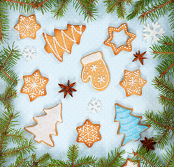 Christmas ginger cookies, star anise, snowflakes and spruce branches on light blue background.