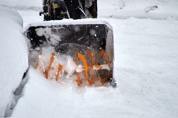 black and orange snowplow cleaning road from the snow