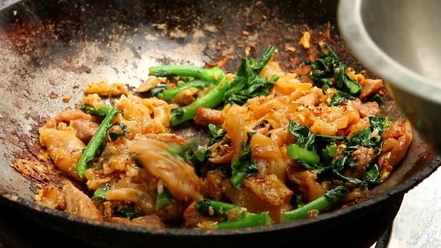 Frying noodle with chopped pork and Chinese kale in pan, Thai street food