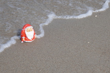 Christmas by the sea. Little garden gnome in Santa Claus costume goes on vacation in the tropics...