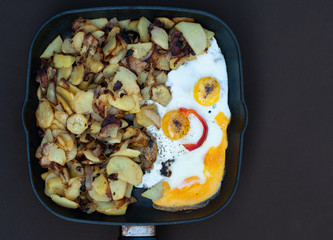 Fried potatoes and scrambled eggs on a pan in form of funny face