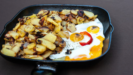 Fried potatoes and scrambled eggs on a pan in form of face
