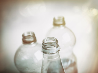 Three plastic bottles have been photographed in a retro style with shallow depth of field with emphasis of the foremost bottle.