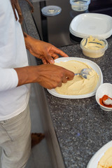 Young African-American With Dreadlocks In The Hair. He is preparing hummus in a modern kitchen.