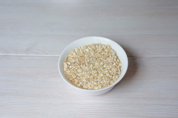 oatmeal in a plate on a light wooden background.