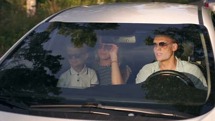 Portrait of a young family in sunglasses with a child in the car during a summer trip. Slow motion.