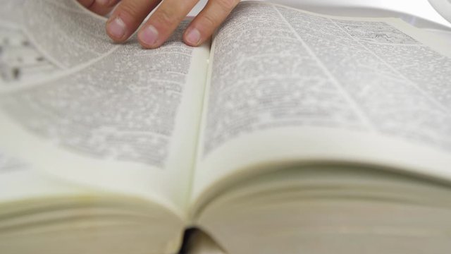 Close up shot of man's hands turning the pages of a reference book. Finds the information.