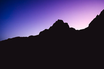 Dreamy photo of a dusk or dawn of mountain alpine landscape. Blue and purple sky above a mountain horizon. Silhouette of a summit or peak of a mountain. Spitzmauer, Totes Gebirge, Austria.