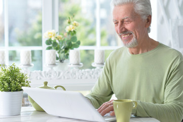 Portrait of emotional senior man using laptop