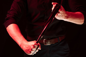 a man holding a leather whip. bdsm