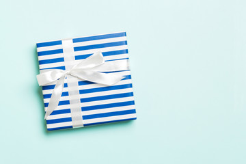Gift box with white bow for Christmas or New Year day on blue background, top view with copy space
