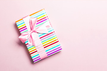 Gift box with pink bow for Christmas or New Year day on pink background, top view with copy space