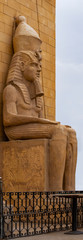 Seated statue of a pharaoh wearing nemes headdress and double crown in Egypt.