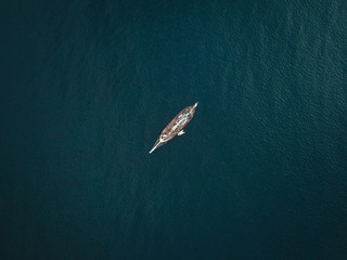 Top down view of a yacht sailing on opened sea. Sailing boat from above.