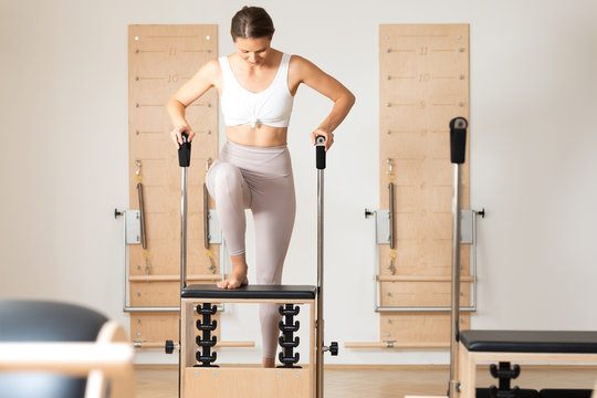Pretty Caucasian woman doing pilates exercise using equipment.
