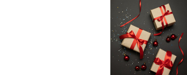 Christmas gift boxes with red bow on dark background with sparkles. Holiday banner for website. Flat lay style composition, top view. Birthday or party greeting card with copy space, hen party invite