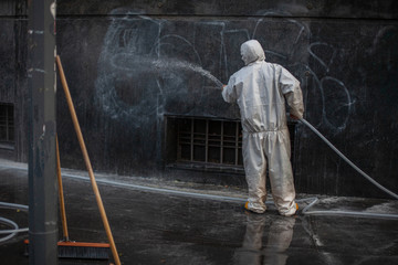 Uomo disinfetta muri strada covid19 sanificazione - obrazy, fototapety, plakaty