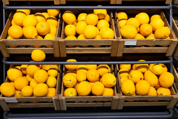 Wooden lug boxes with ripe lemons on counter in supermarket