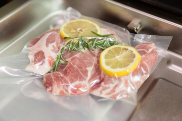 Sous vide steak with rosemary and lemons in vacuumed package.