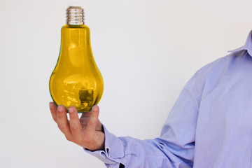 businessman in blue shirt holds in his hand a big yellow lamp, concept is electrifying, an idea, copy space