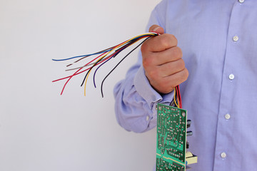 man in a shirt holds a torn computer board with colored wires