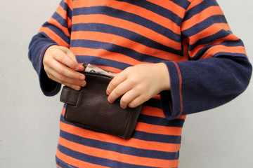 child, preschooler, primary school student, takes out money, dollars, euros from a leather wallet, hands close-up