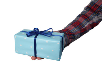 male hand holds out a gift in blue paper with a ribbon on a light background, concept of Valentine's Day, Christmas presents, close-up, copy space