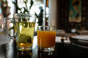 glass of tea and orange juice on wooden table in a cafe