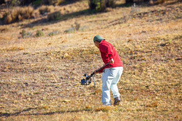 person making video the field with camera and stabilizer