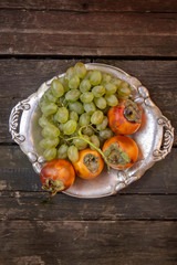 persimmons and grapes on a vintage metal plate