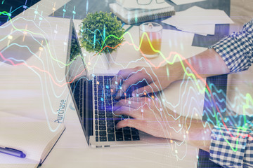 Multi exposure of graph with man typing on computer in office on background. Concept of hard work. Closeup.