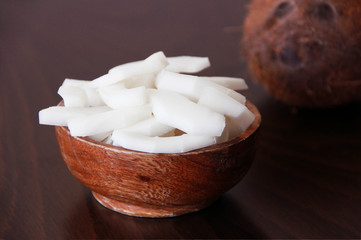 brown coconut fruit and slices of natural white coconut in a wooden plate