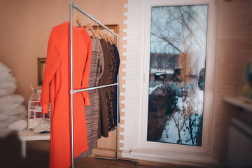 the concept of tailoring, clothing for women casual style, fashion, accessories. Dresses hanging on a hanger by the window