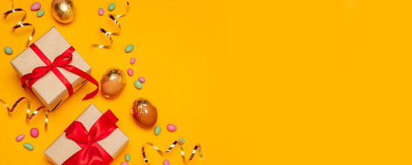 Fototapeta premium Gift craft boxes with red bows and golden eggs on a yellow background.