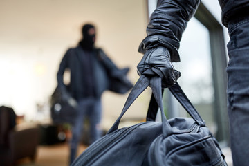 Einbrecher tragen Tasche mit Beute aus Haus