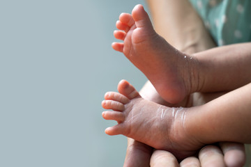 Mother holding tiny foot of newborn baby skin