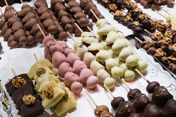 Fruits bananas, strawberries, nuts, apples, peaches drenched in white and dark chocolate. 