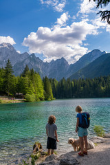 Tourist with their dog enjoy beautiful land scape of Lago di Fusine, the lake with background of Julian alps in Italy.