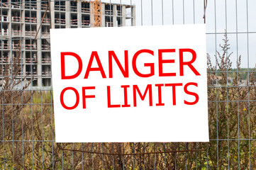 A construction fence enclosing a building on which warning information hangs