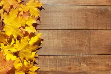 Naklejka na ściany i meble Fall leaves background. Welcome Autumn concept. Yellow maple leaves on brown wooden table. September, October, November, thanksgiving, border, frame