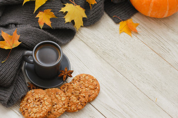 Grey cup of coffee, cookies, spices, scarf, yellow maple leaves, orange pumpkin on white wooden...