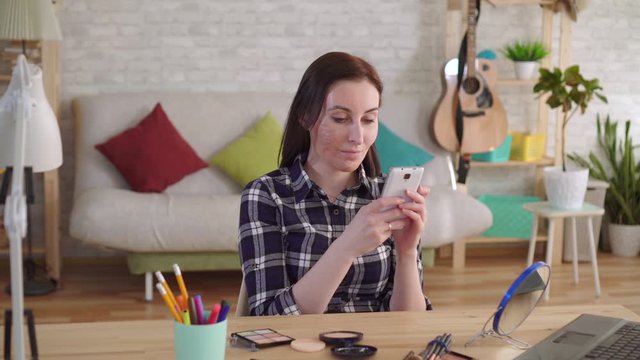 joyful Young woman with a burn scar on her face using a smartphone
