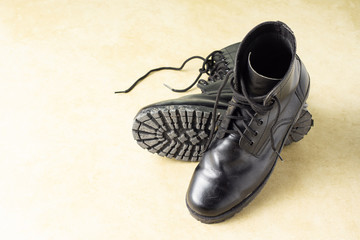 Used black genuine leather combat boots on the grunge floor