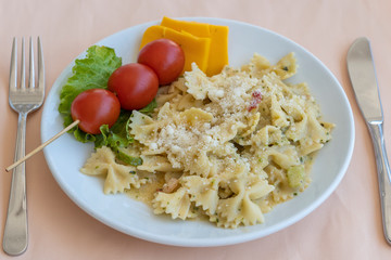Pasta farfalle with cherry tomato and cheese in white plate, closeup